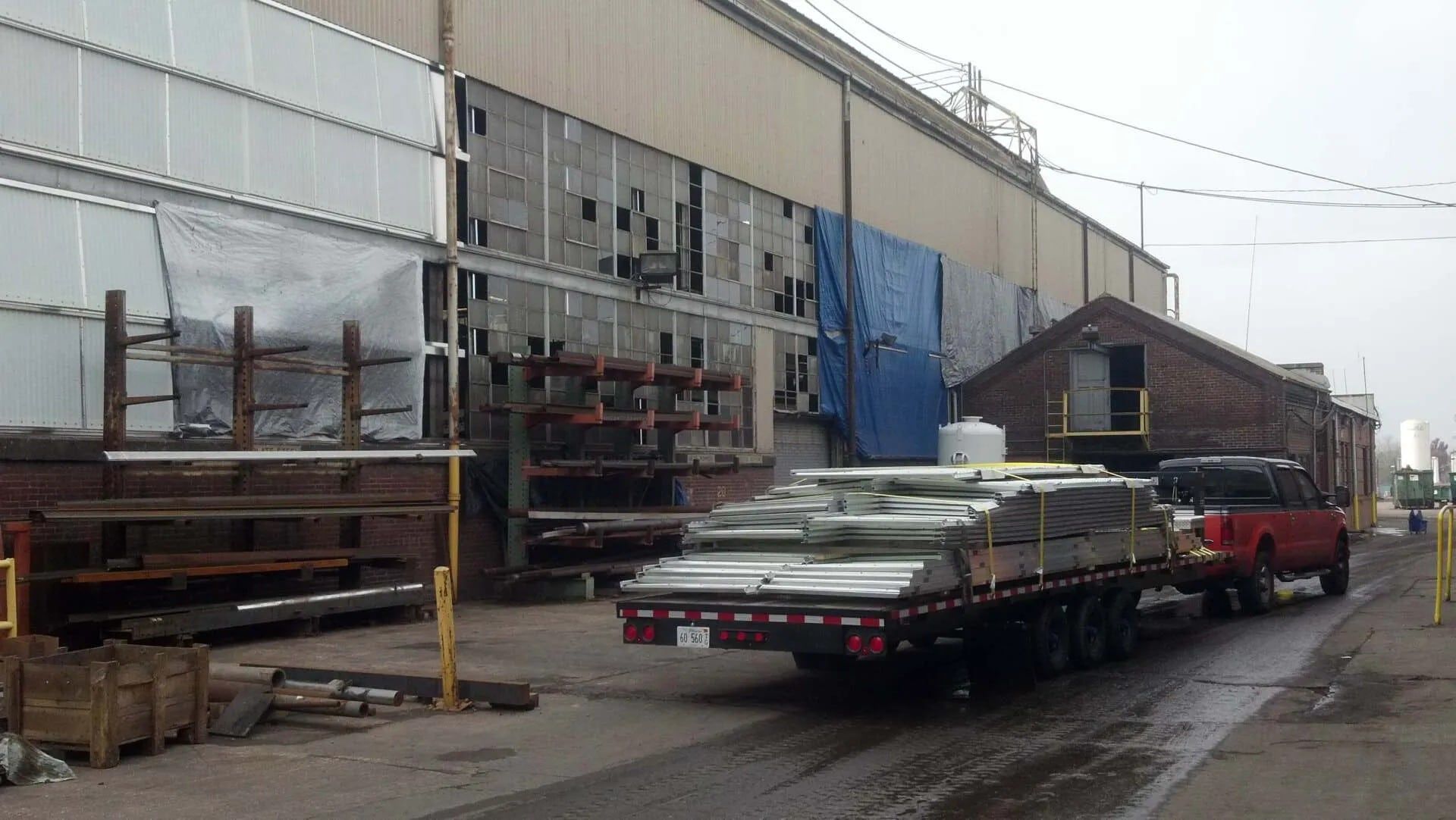 A red truck is carrying a trailer full of metal pieces