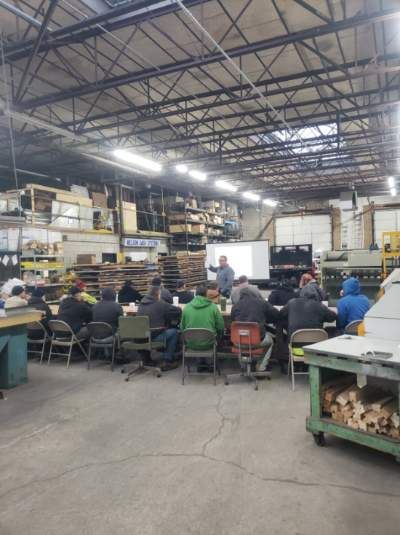 A group of people are sitting at tables in a warehouse