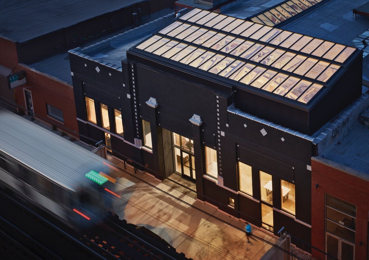 An aerial view of a train going by a building at night