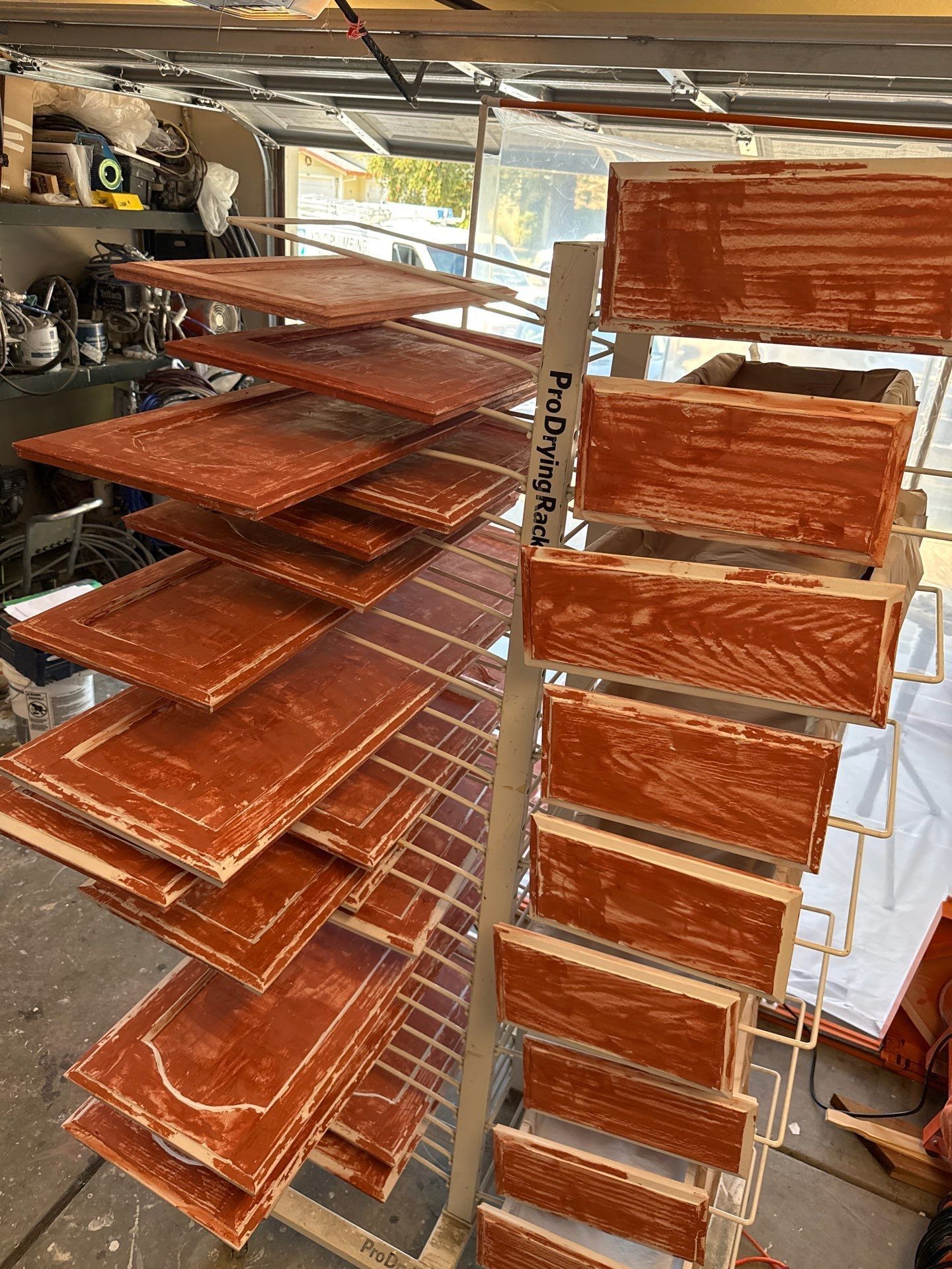 Stacks of orange-brown trays or shelves drying in a workshop with sunlight streaming in.