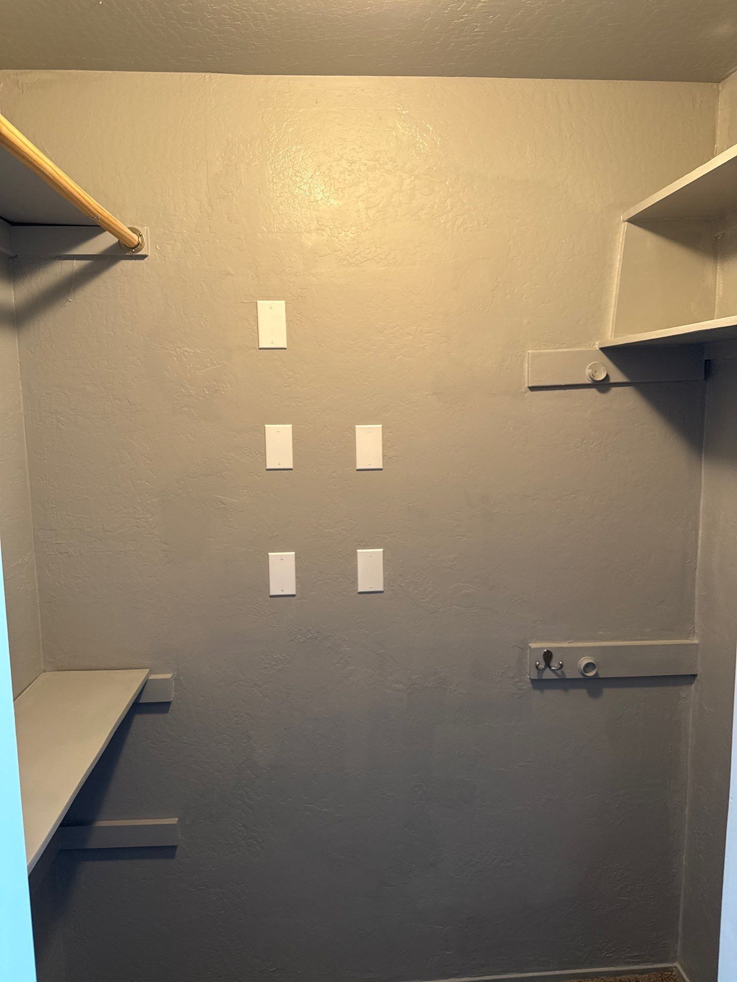 Empty gray closet with shelves and wall-mounted hooks for storage