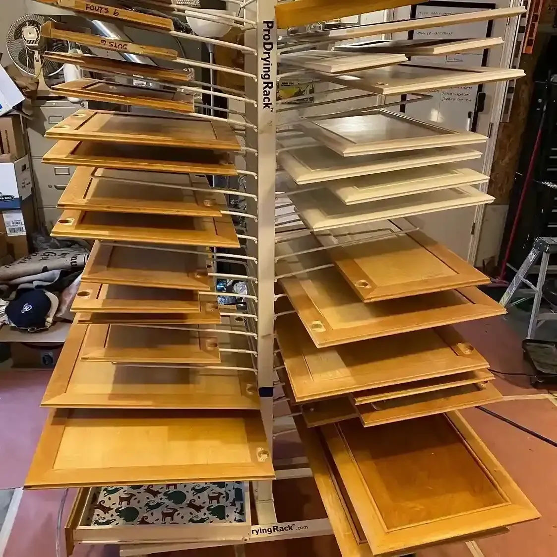 Rows of wooden shelving panels stacked on metal racks in a workshop or warehouse.
