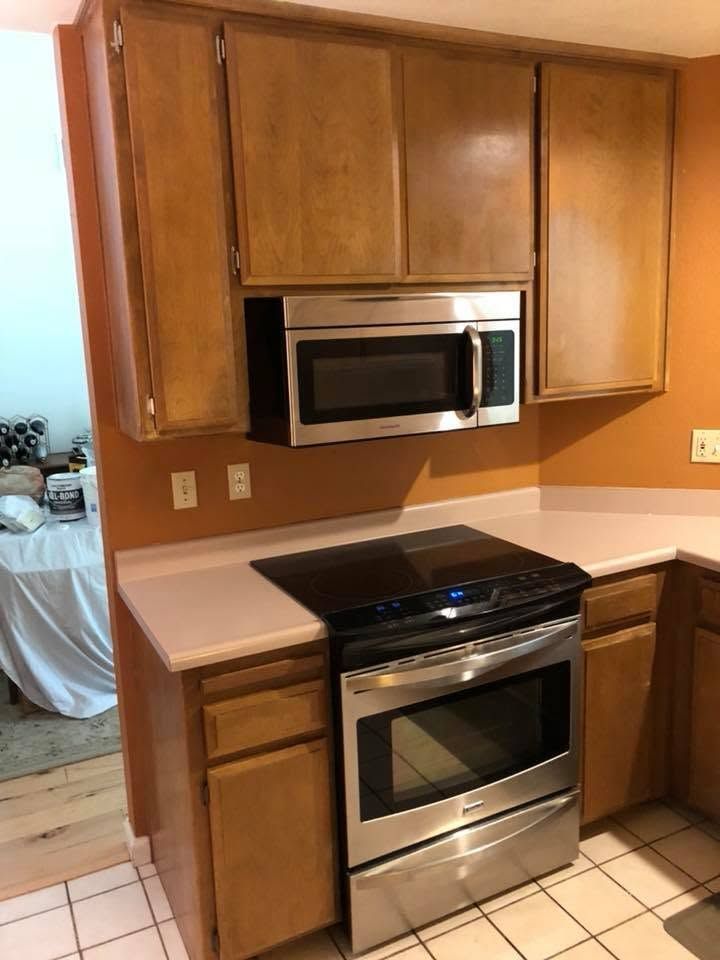 Kitchen with wood cabinets, stainless steel oven, built-in microwave, and light countertop