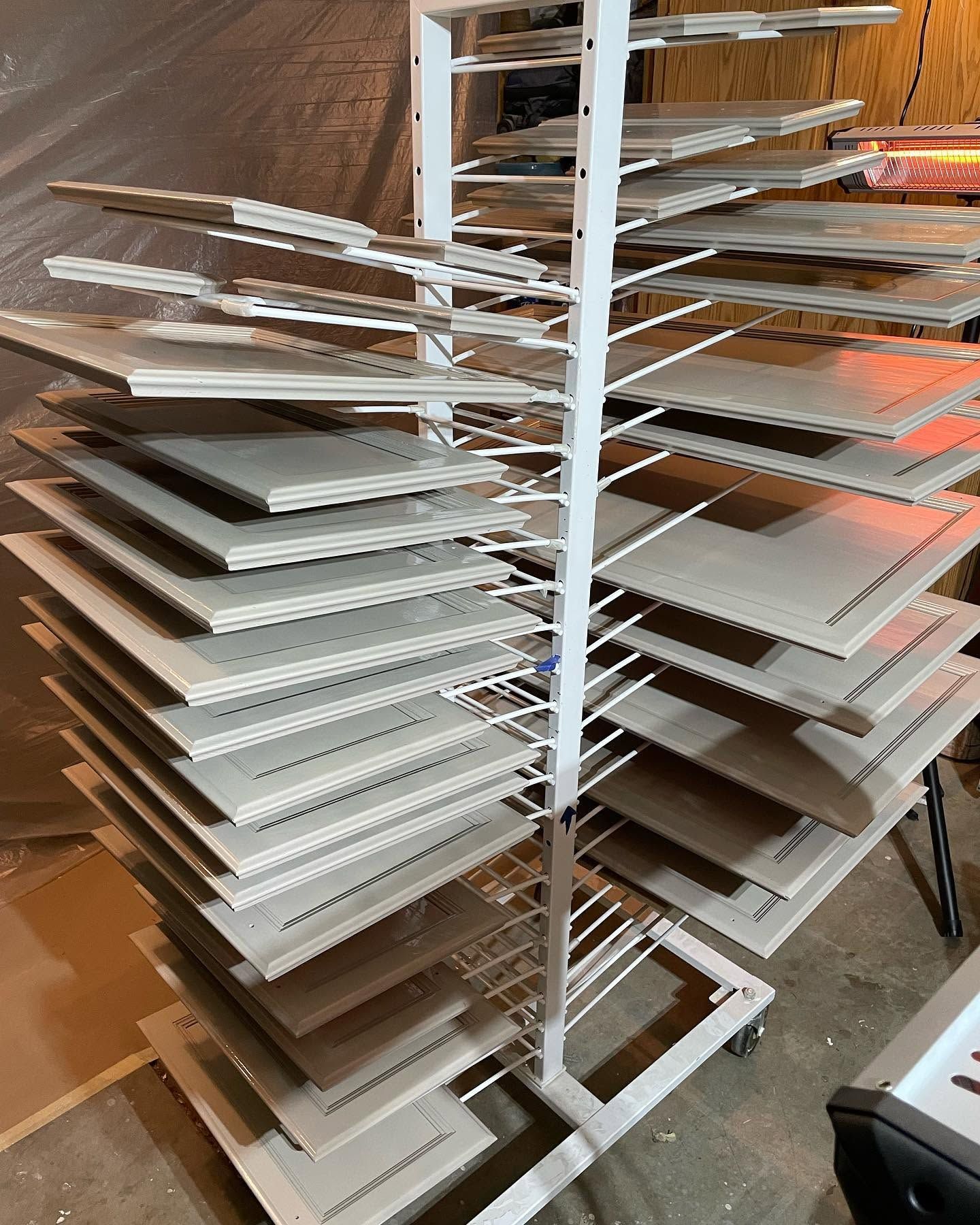 Rotating rack loaded with stacked white rectangular panels in a workshop or store