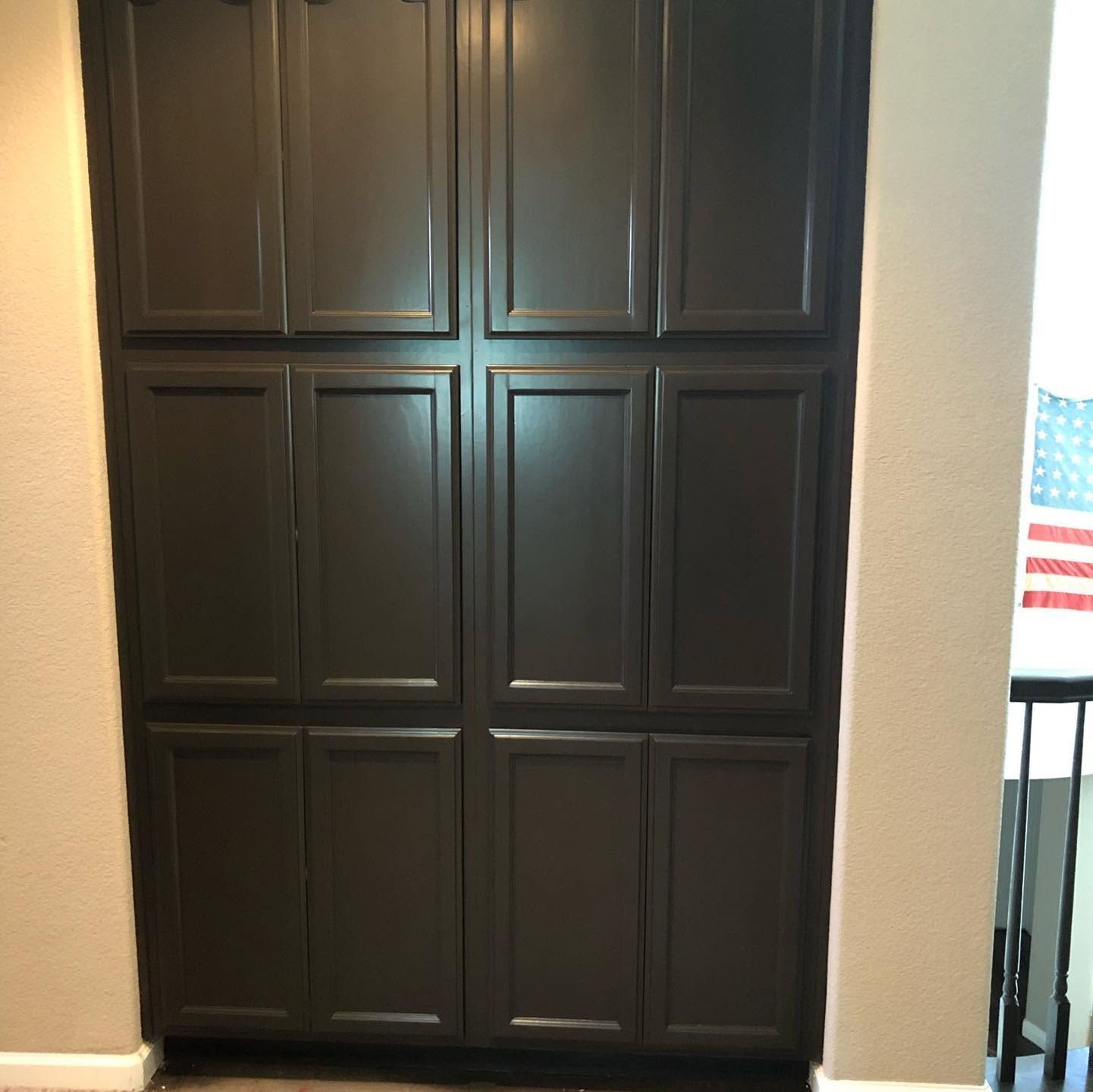 Dark brown paneled cabinet doors beside a sunlit wall, with a partial American flag visible on the right.