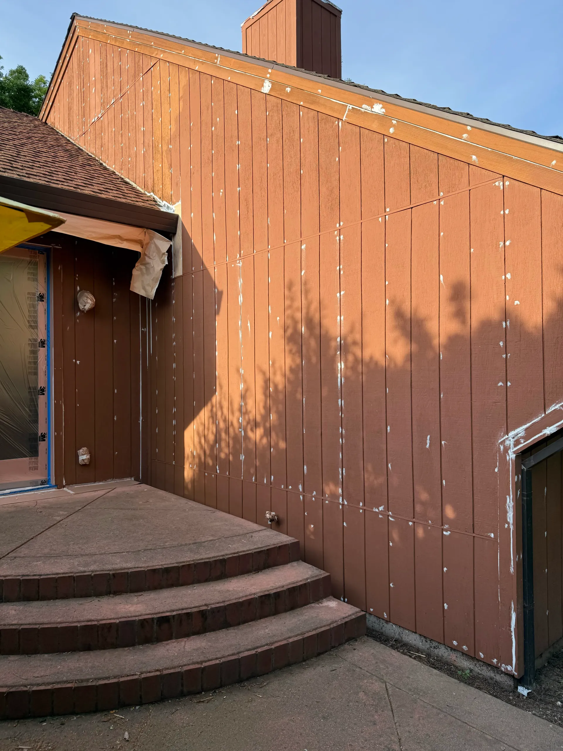 Curved concrete steps leading to a brown wooden building wall with a small door and steep roofline