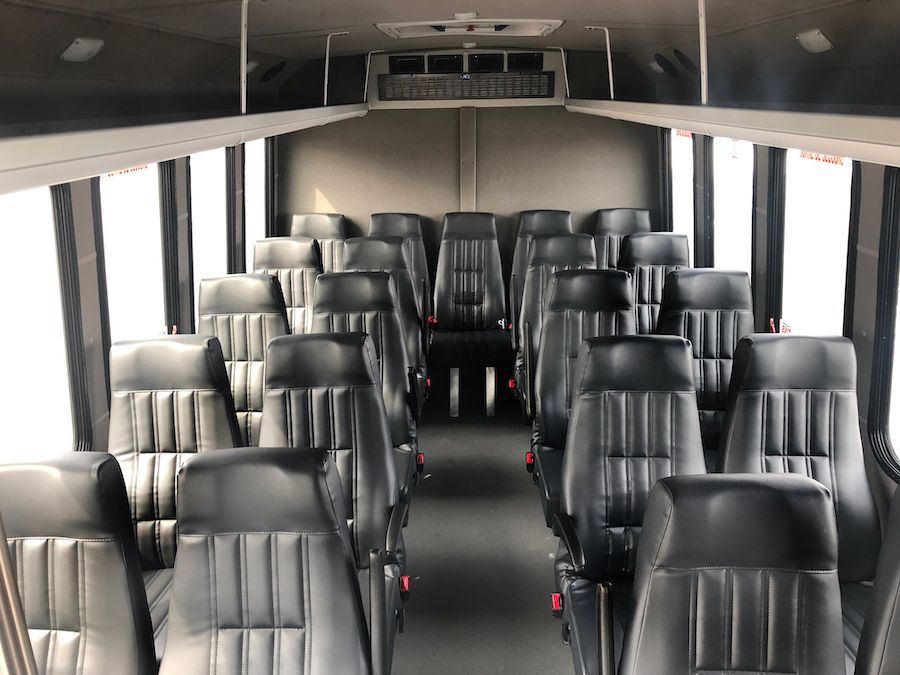 Empty bus interior with rows of black seats and large side windows