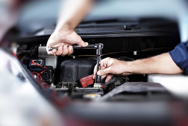 A Man is Working on the Engine of a Car With a Wrench — Mick Dunn Motor Repairs in Mackay, QLD