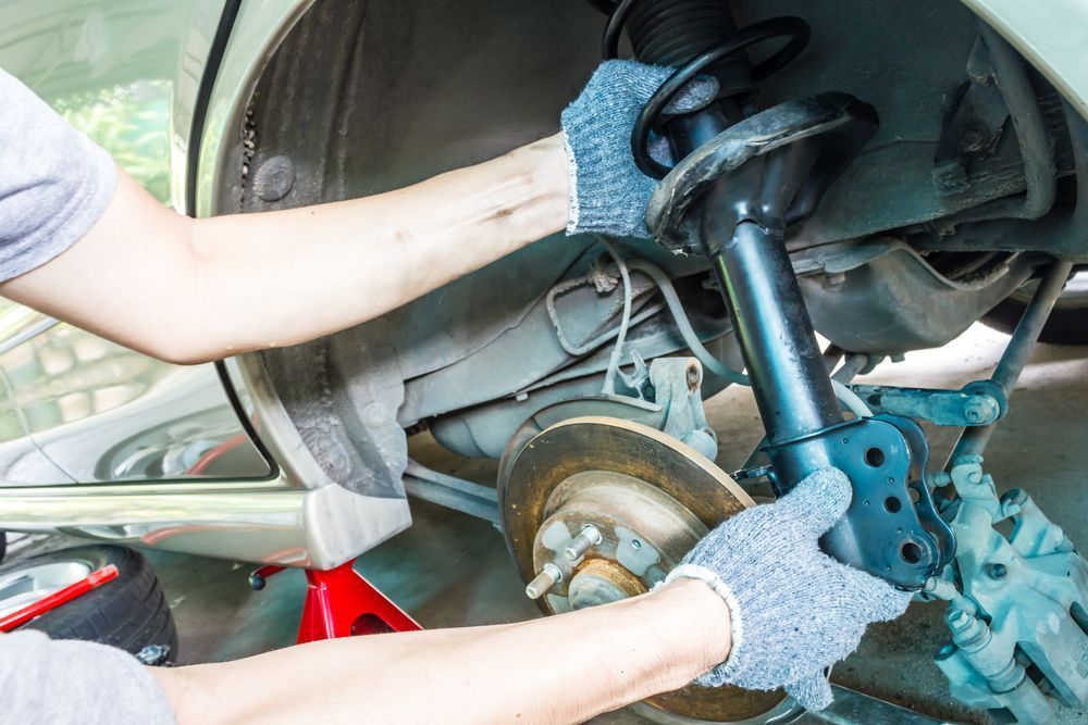 A Man is Working on the Suspension of a Car — Mick Dunn Motor Repairs in Mackay, QLD