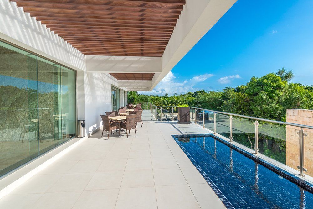A Large Balcony with A Swimming Pool and Tables and Chairs — Coastline Glass Pool Fencing in Hallidays Point, NSW