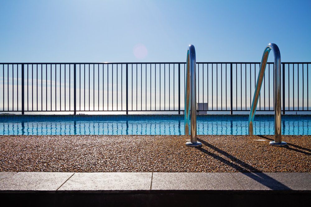 A Swimming Pool with A Fence Around It and Stairs Leading to It — Coastline Glass Pool Fencing in Forster, NSW