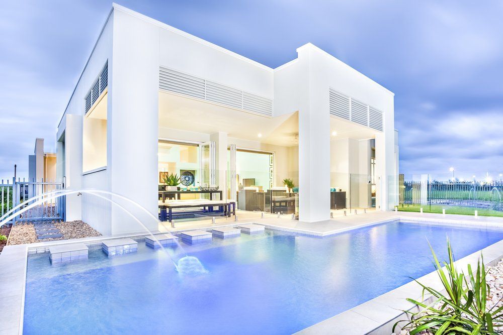 A White House with A Large Swimming Pool in Front of It — Coastline Glass Pool Fencing in Nabiac, NSW