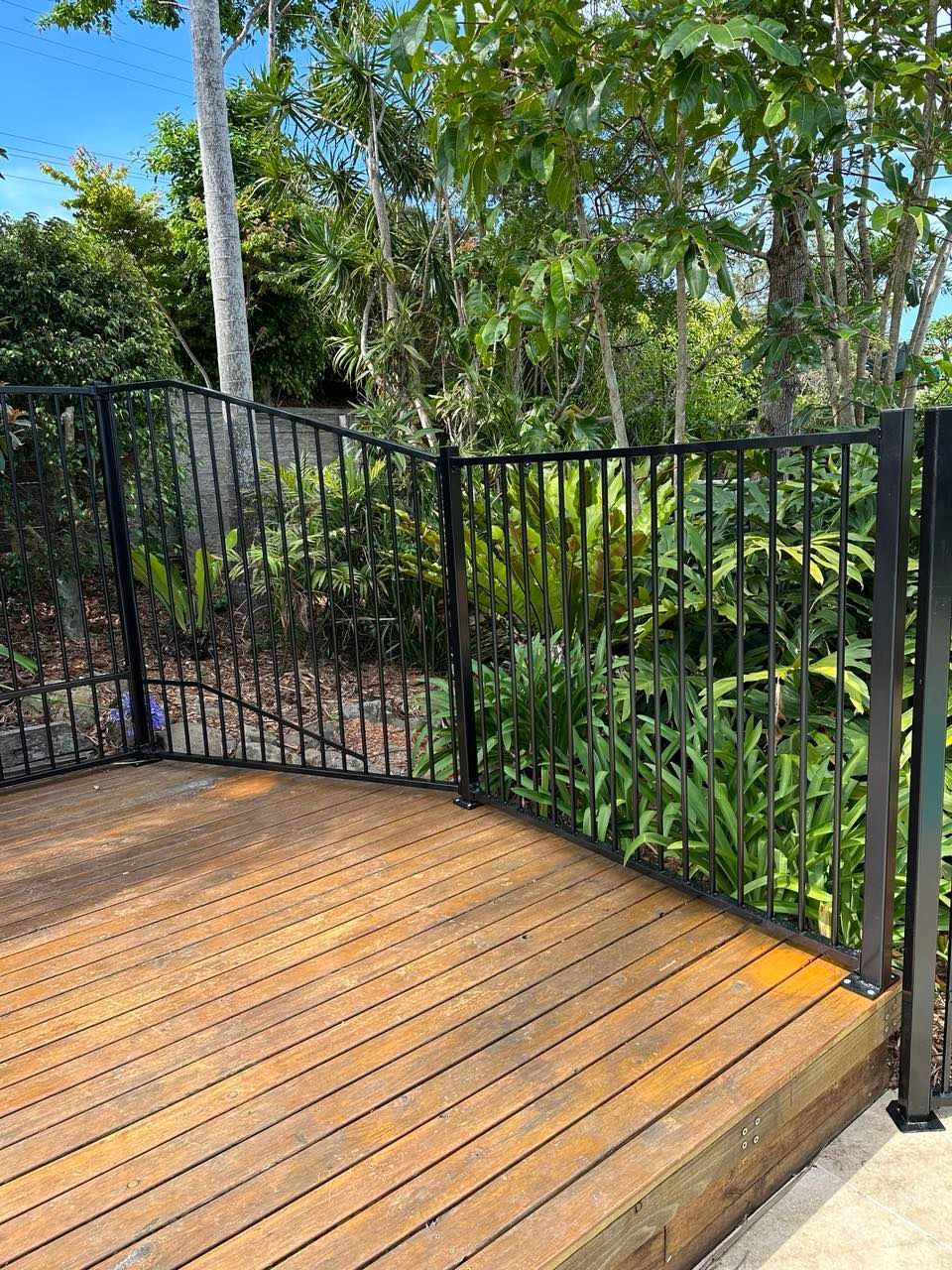 A Wooden Deck with A Black Metal Railing — Coastline Glass Pool Fencing in Old Bar, NSW