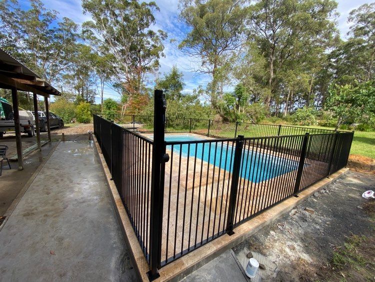 A Rectangular Swimming Pool Enclosed by A Black Metal Fence — Coastline Glass Pool Fencing in Laurieton, NSW