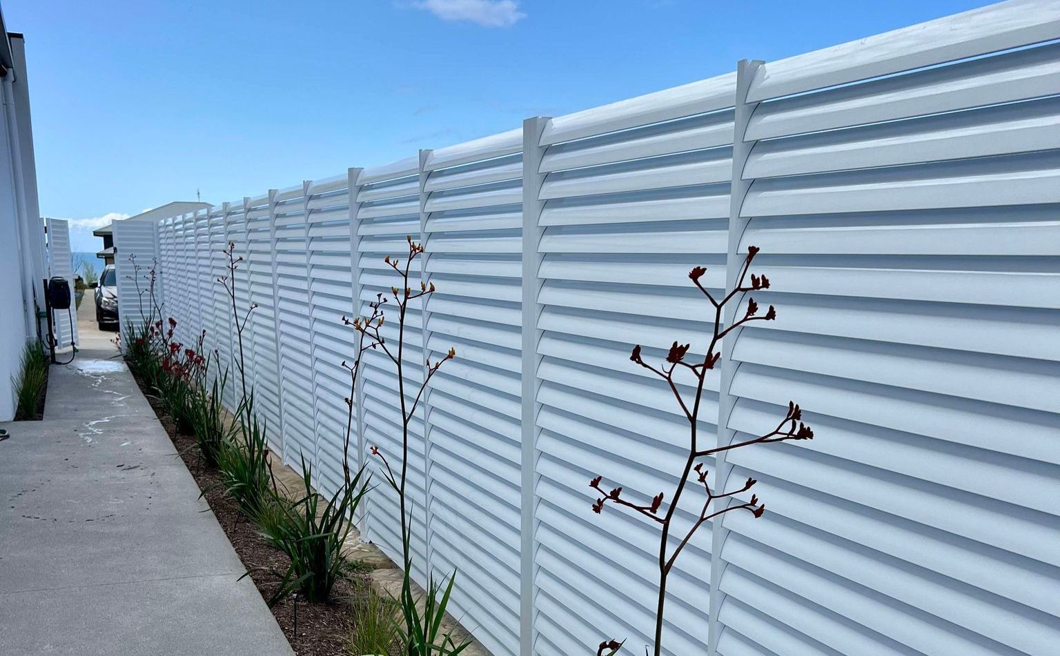 A Concrete Walkway Runs Alongside a Tall White Horizontal Slat Fence — Coastline Glass Pool Fencing in Old Bar, NSW