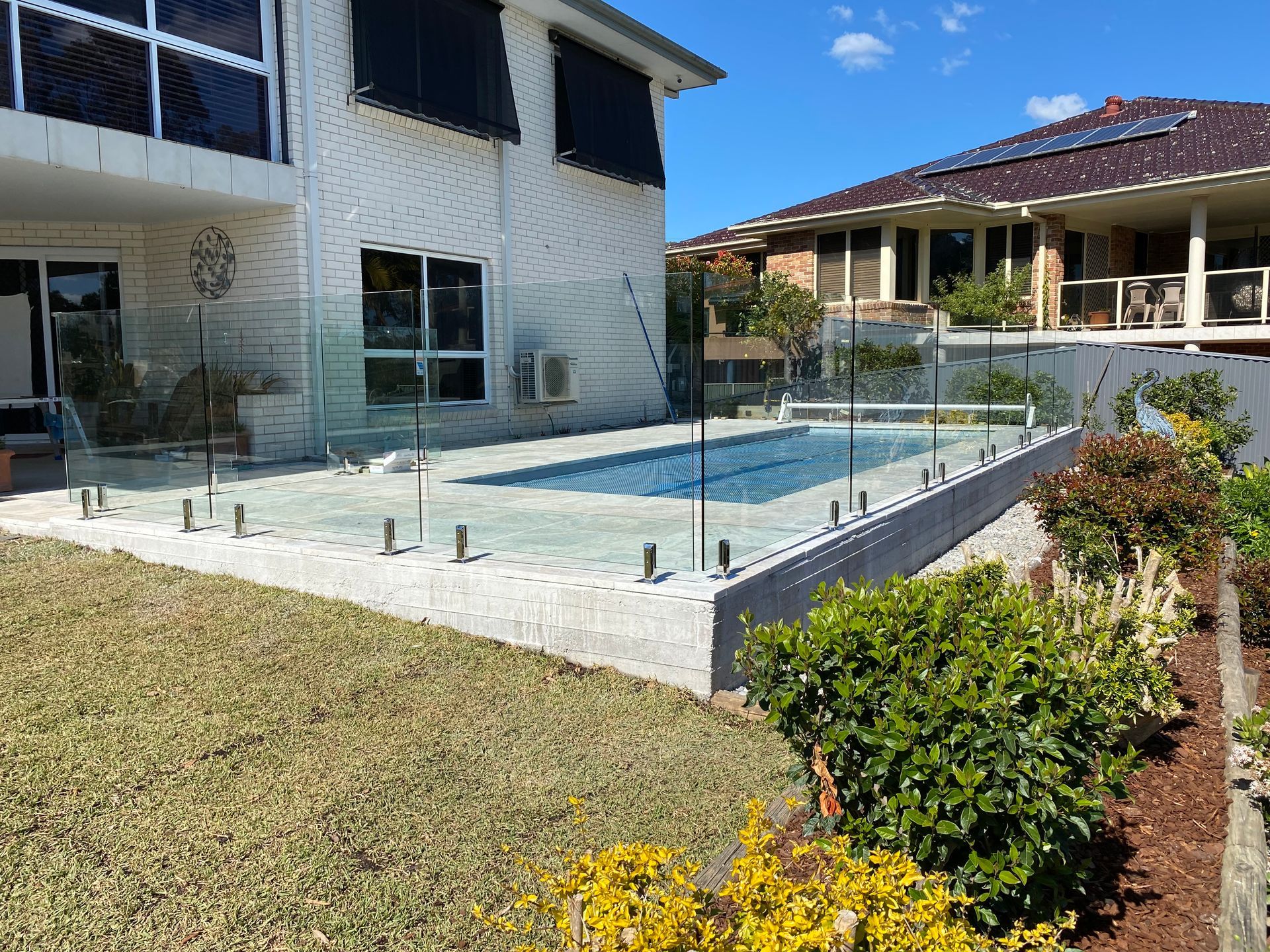 A Large House with A Swimming Pool in Front of It — Coastline Glass Pool Fencing in Old Bar, NSW