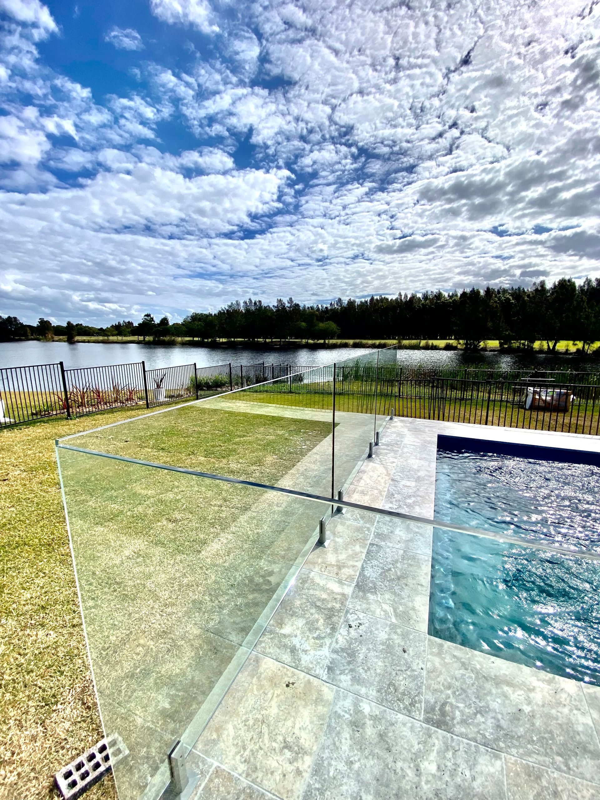 A Swimming Pool with A Glass Railing and A View of A Lake — Coastline Glass Pool Fencing in Old Bar, NSW