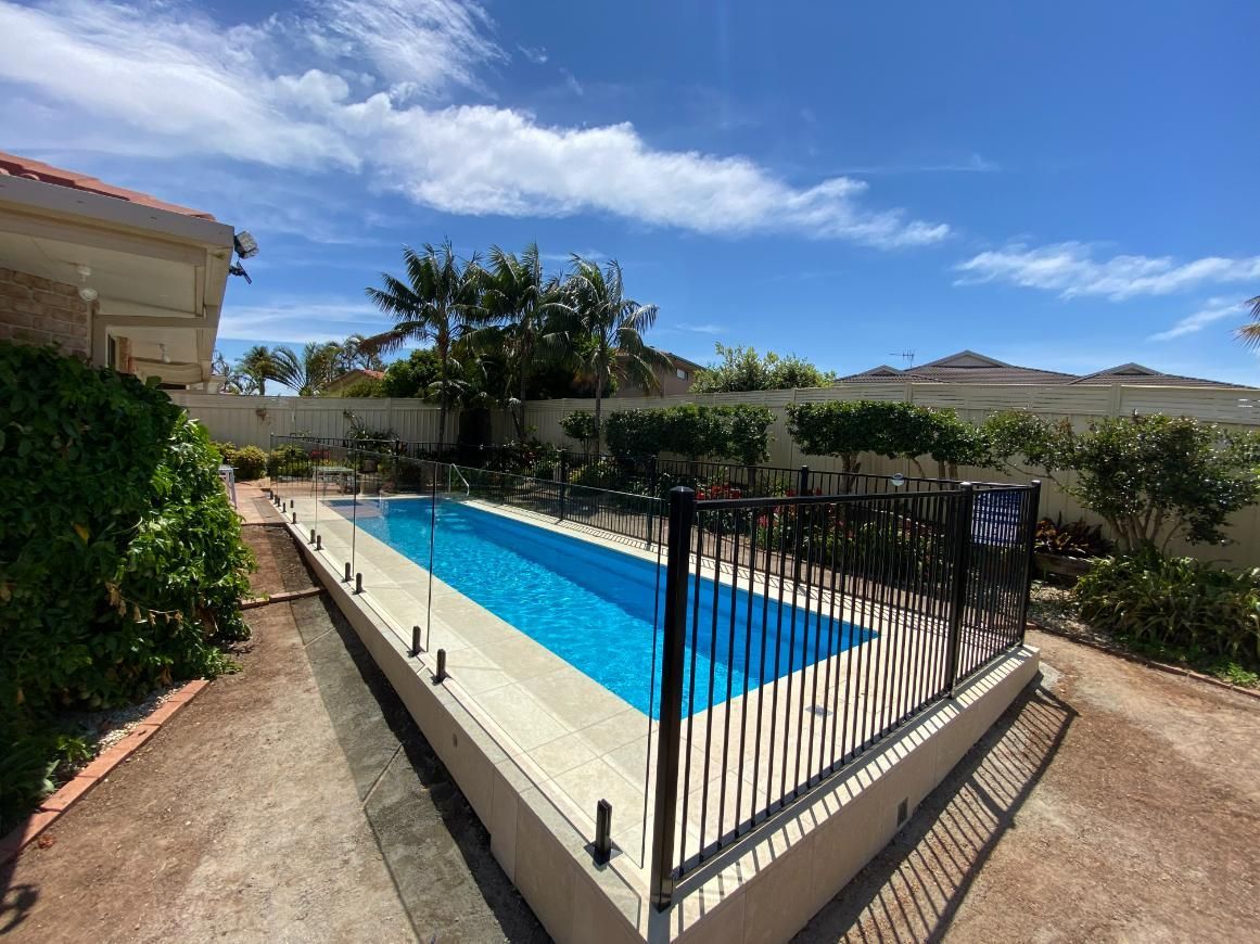 A Backyard Swimming Pool with Blue Water — Coastline Glass Pool Fencing in Old Bar, NSW
