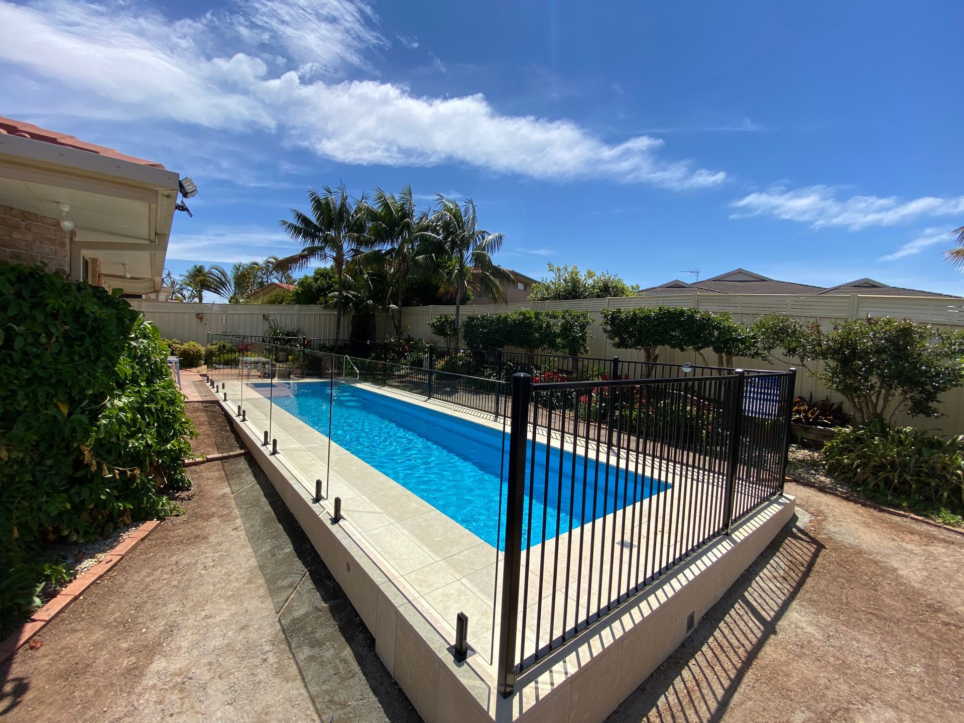 A modern house with a swimming pool and a wooden deck — Coastline Glass Pool Fencing in Old Bar, NSW
