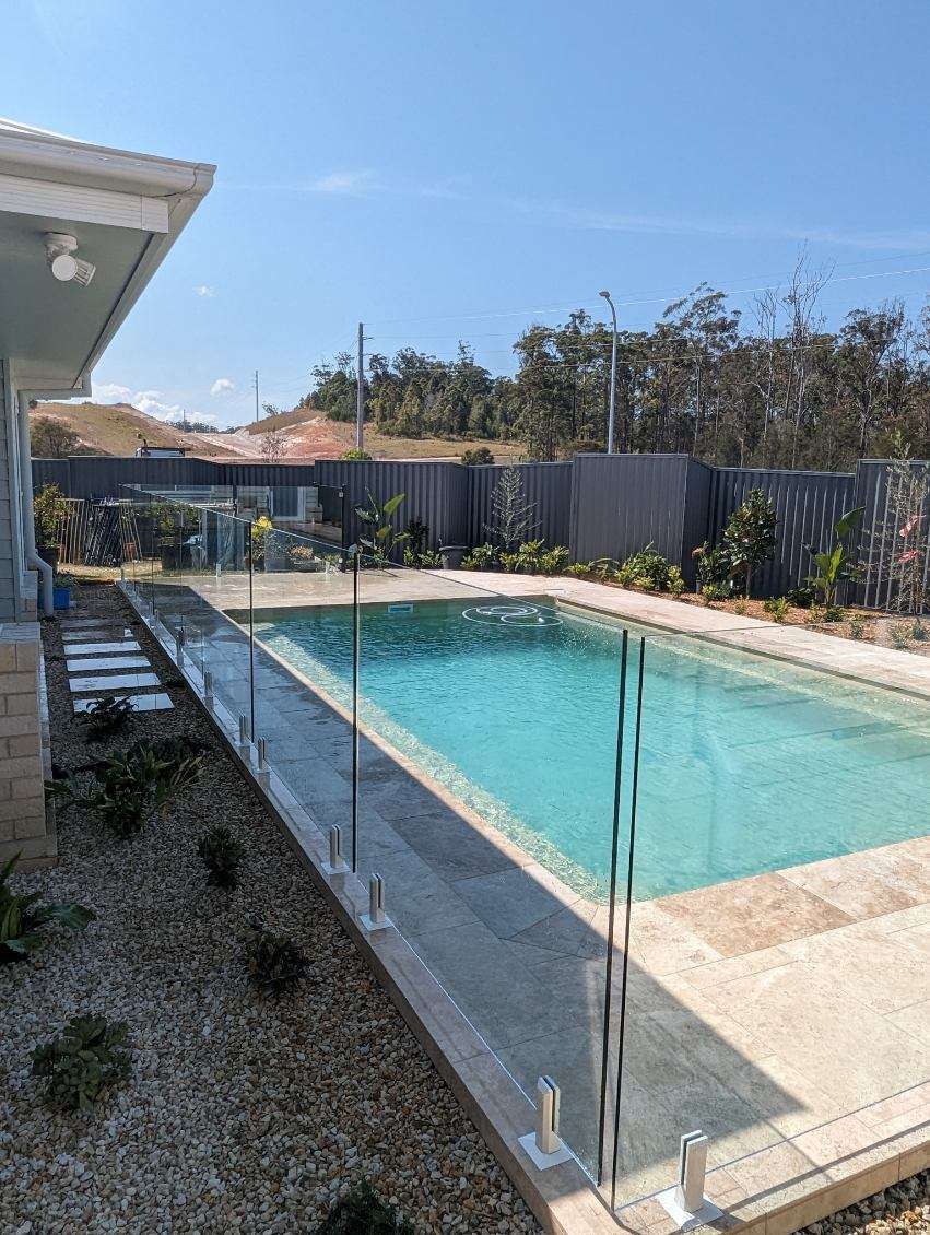 A Rectangular Swimming Pool with Light Blue Water and Stone Pavers — Coastline Glass Pool Fencing in Old Bar, NSW
