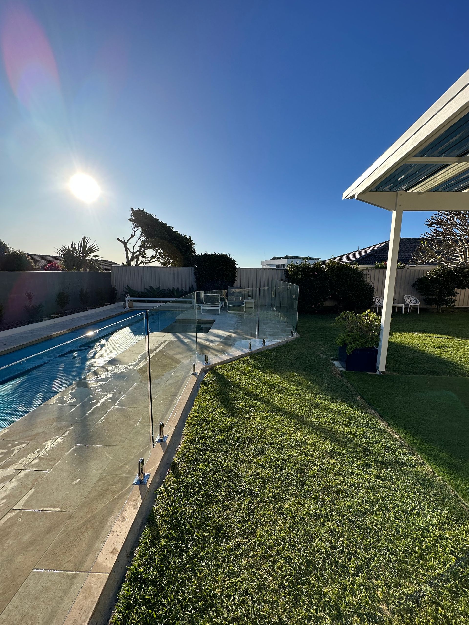 A Backyard Swimming Pool with A Glass Fence, a Lawn, and A Patio — Coastline Glass Pool Fencing in Tuncurry, NSW