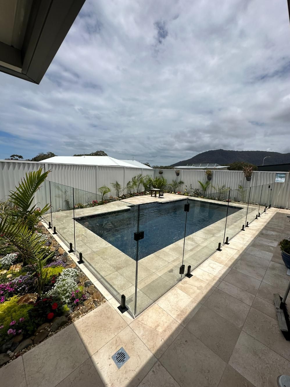 A Large Swimming Pool with A Glass Fence Around It — Coastline Glass Pool Fencing in Old Bar, NSW