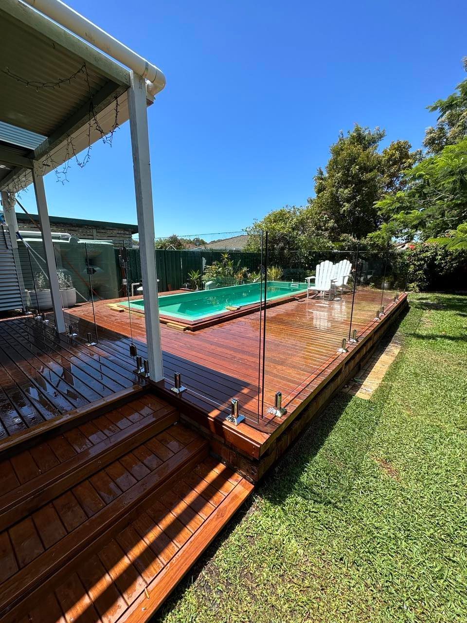 A Large Swimming Pool Surrounded by Chairs and A Fence — Coastline Glass Pool Fencing in Old Bar, NSW