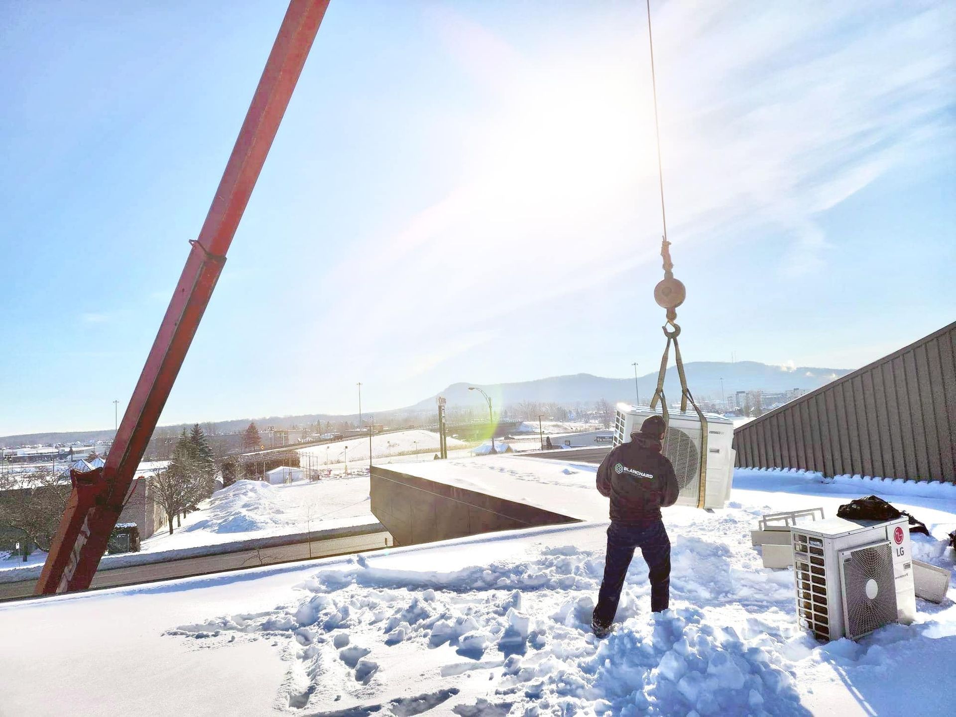 Un homme se tient debout dans la neige à côté d'une grue.