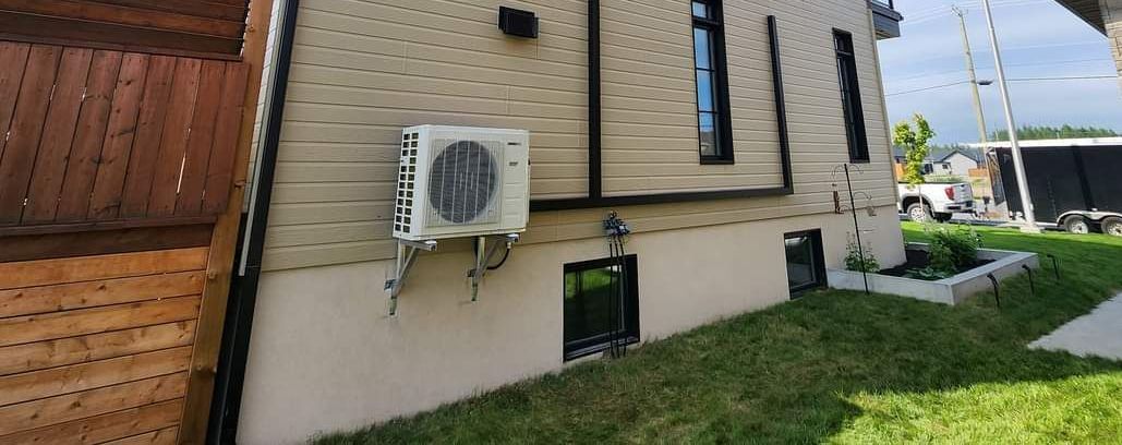 Une photo d'une maison avec un climatiseur sur le côté.
