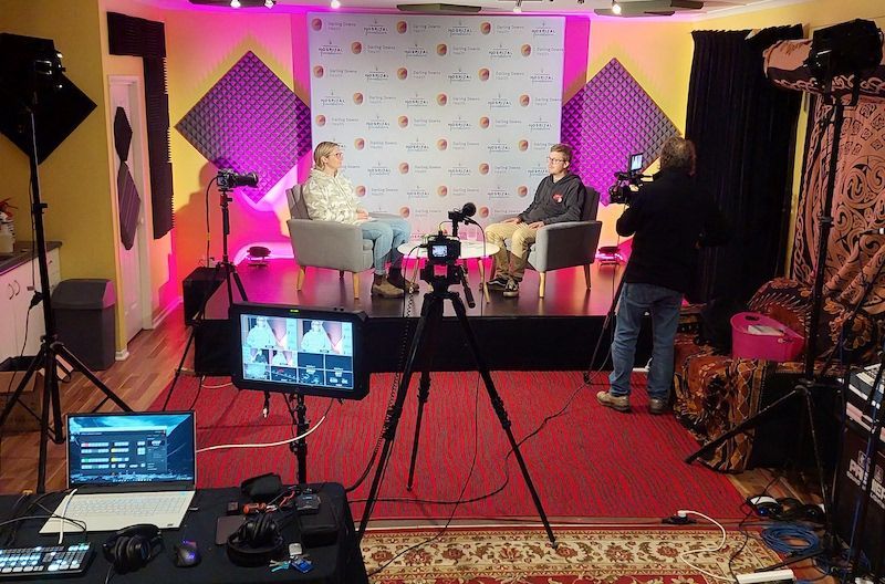 A group of people are sitting in front of a camera in a room