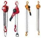 Four chain hoists in red and orange, hanging vertically with hooks and load chains.