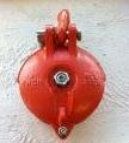 Red circular wall-mounted fire alarm bell with a small central lens on a white wall