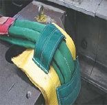 Coiled yellow, green, and red woven tubes on a gray pavement beside a curb