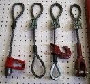 Three climbing carabiners with black lanyards, plus two red and one black attached devices on a pegboard.