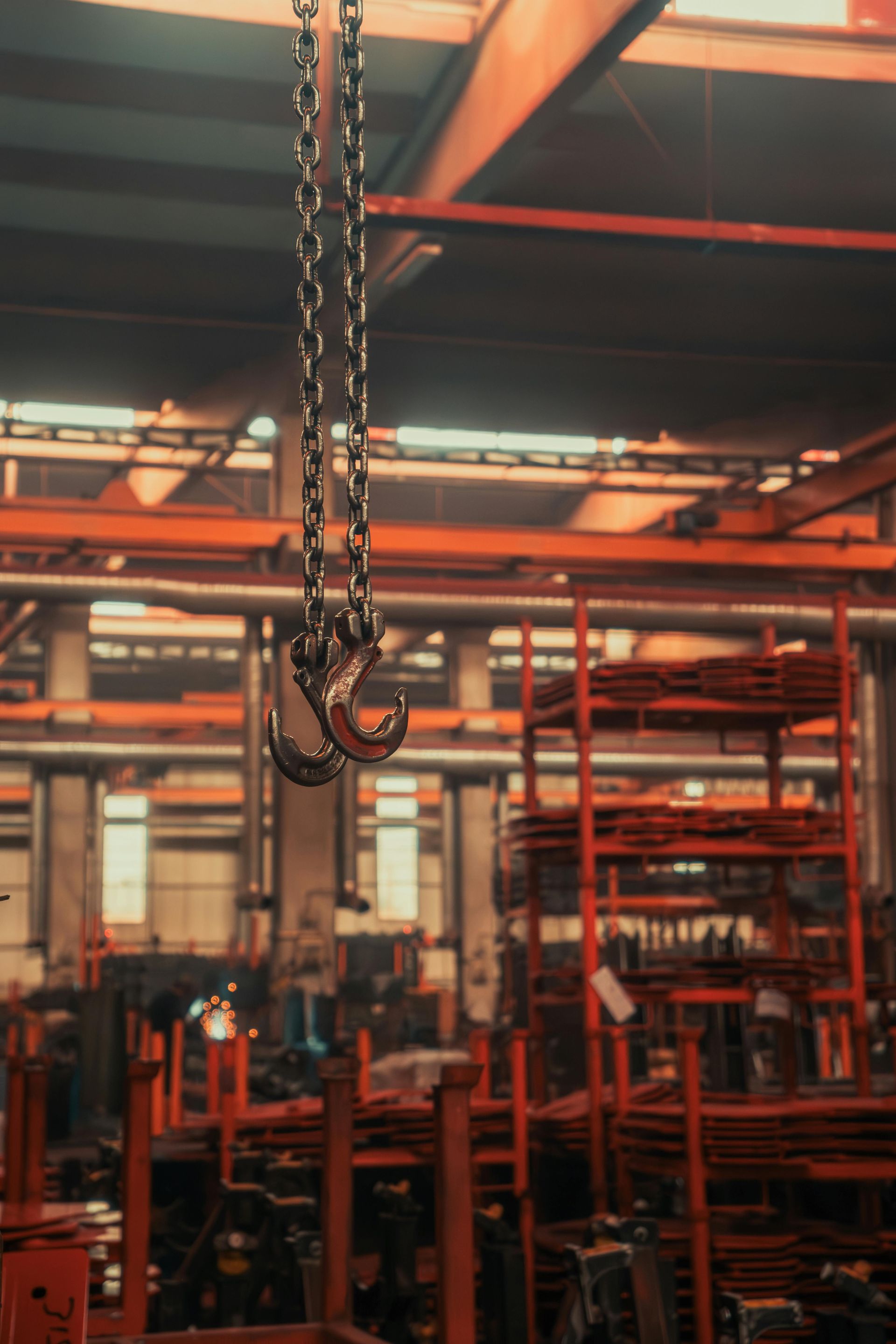 Hanging chain hoist in an industrial warehouse with red metal racks and beams