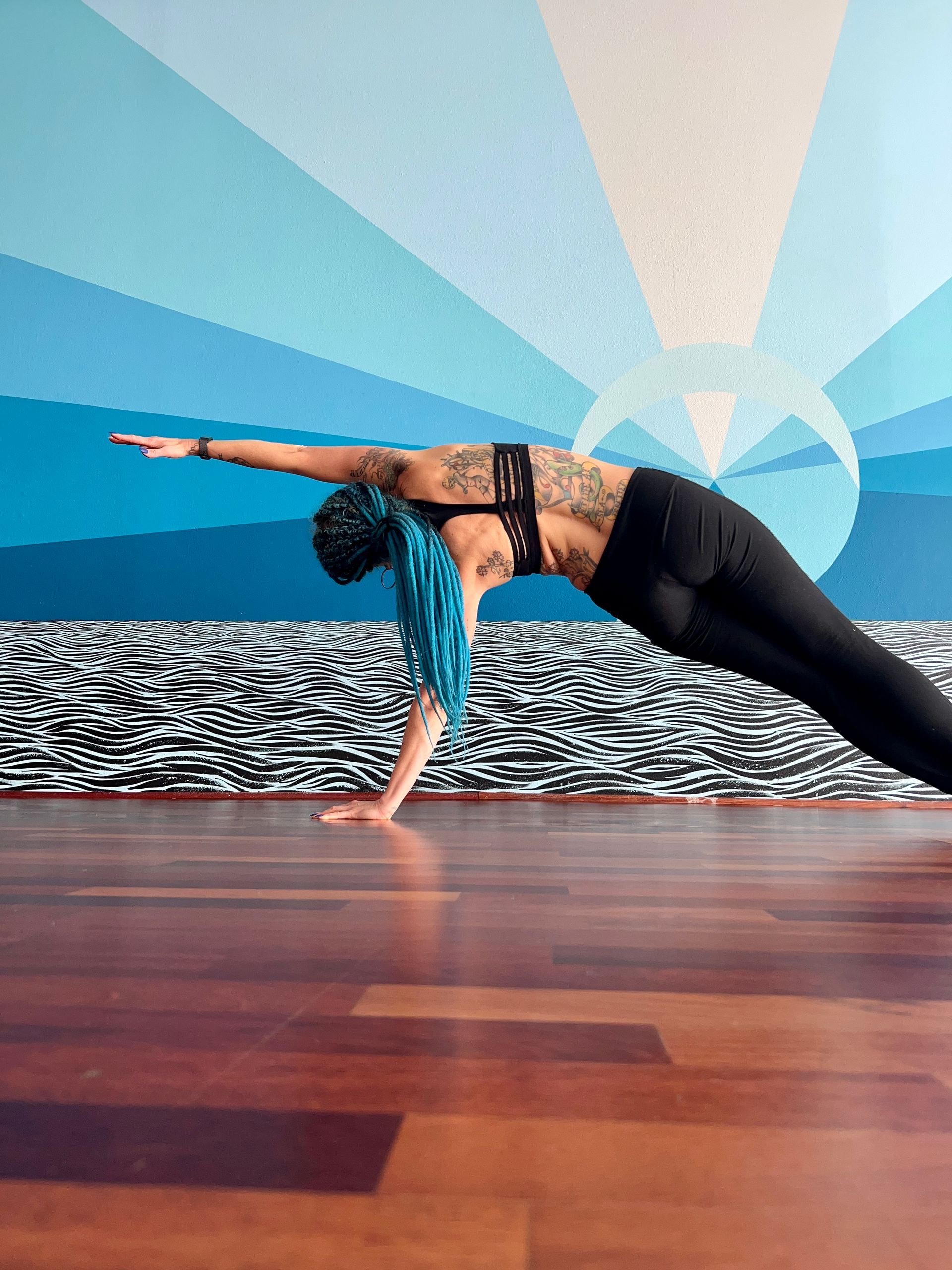 Teacher April in Side Plank pose on blue background