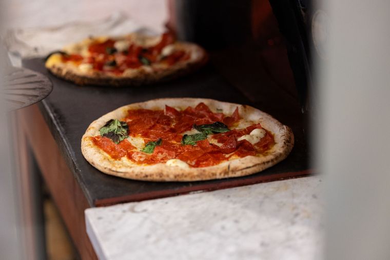 Margherita pizza with tomato sauce, basil leaves, and melted cheese on a metal tray