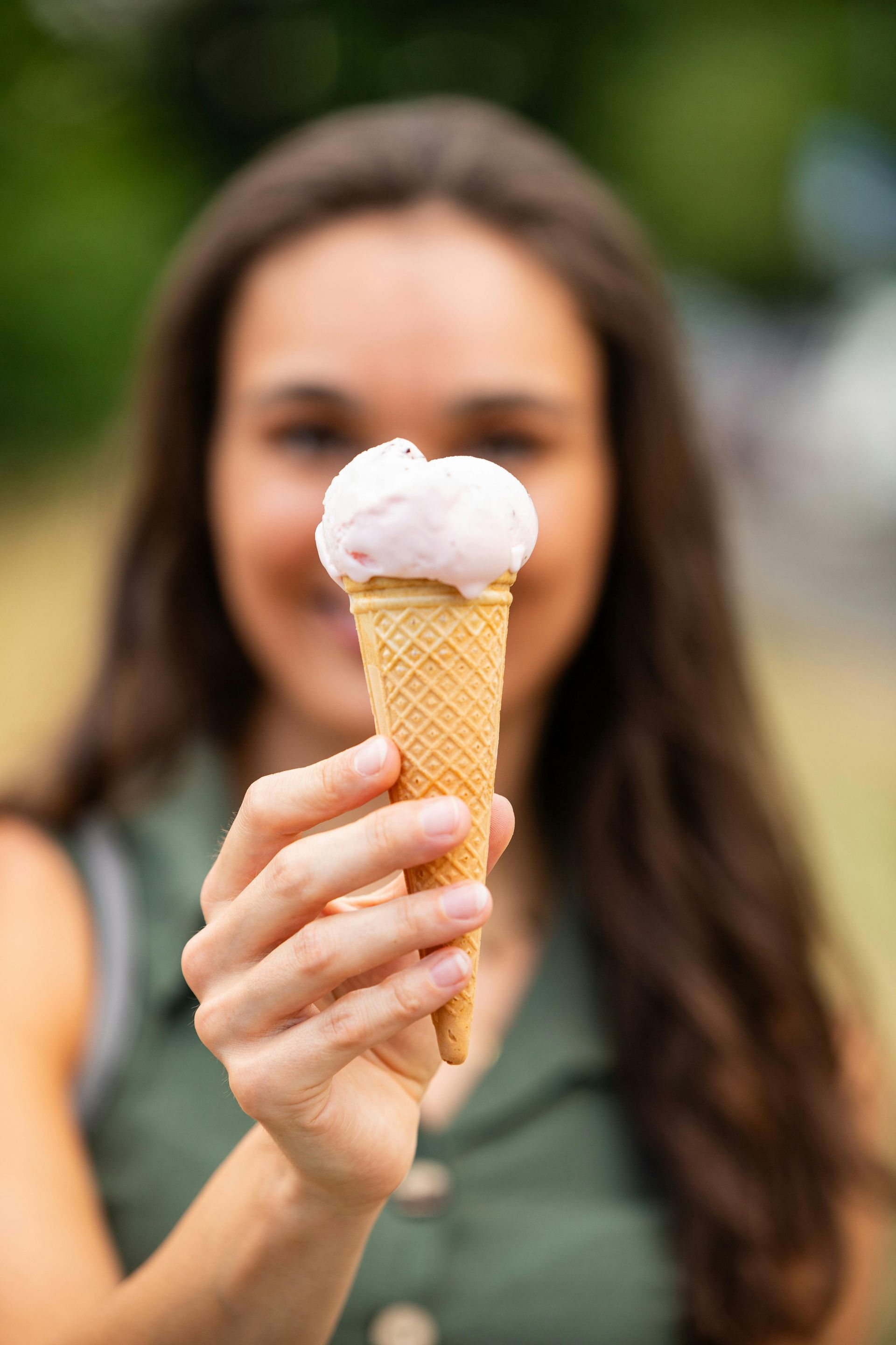 A woman is holding an ice cream cone in front of her face.