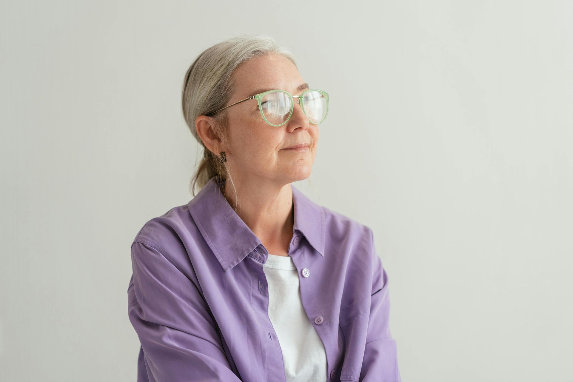 A woman wearing glasses and a blue jacket is smiling.