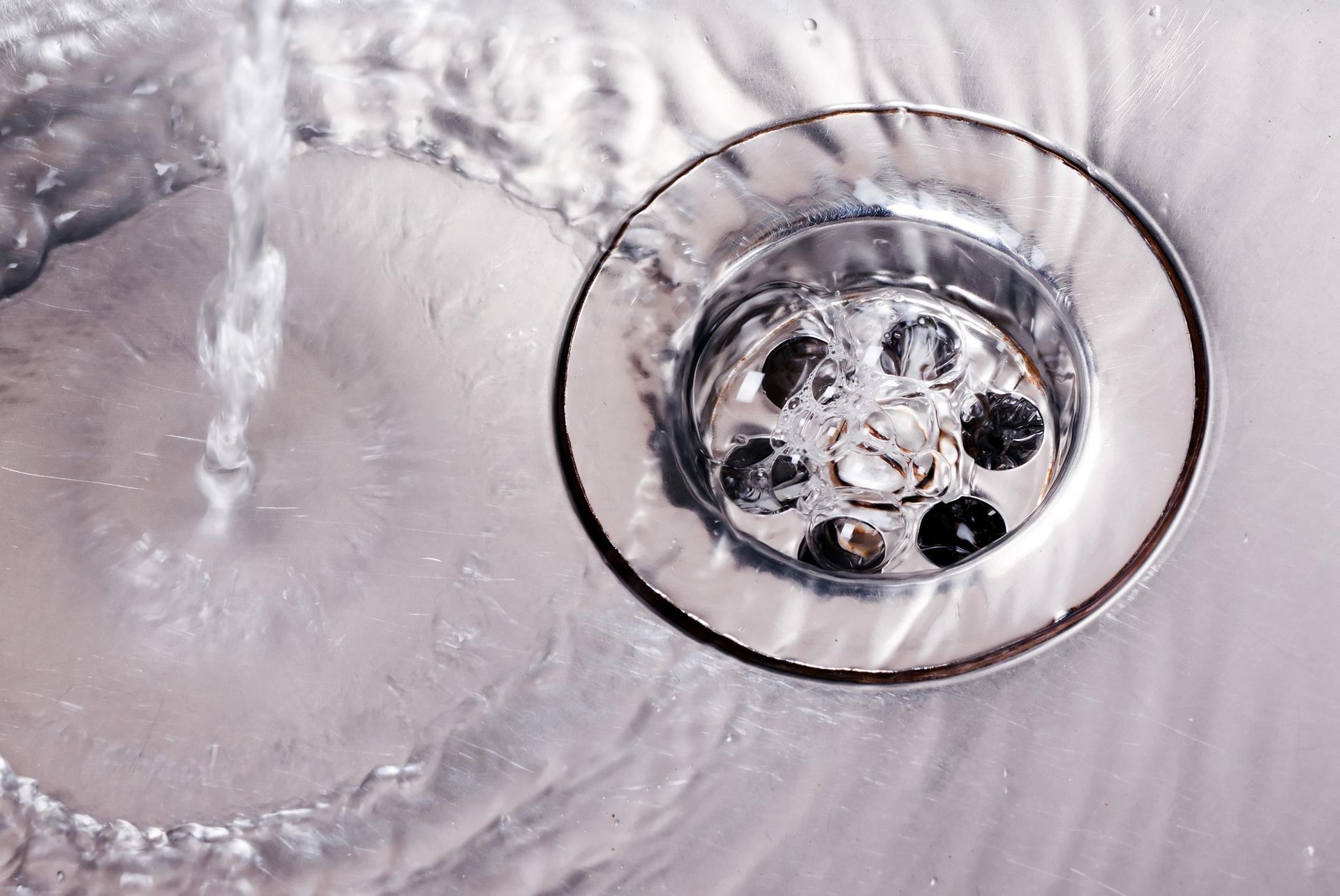 A close up of a sink drain with water running down it.