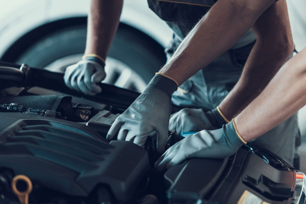 Zwei Mechaniker arbeiten mit Handschuhen an einem Automotor.