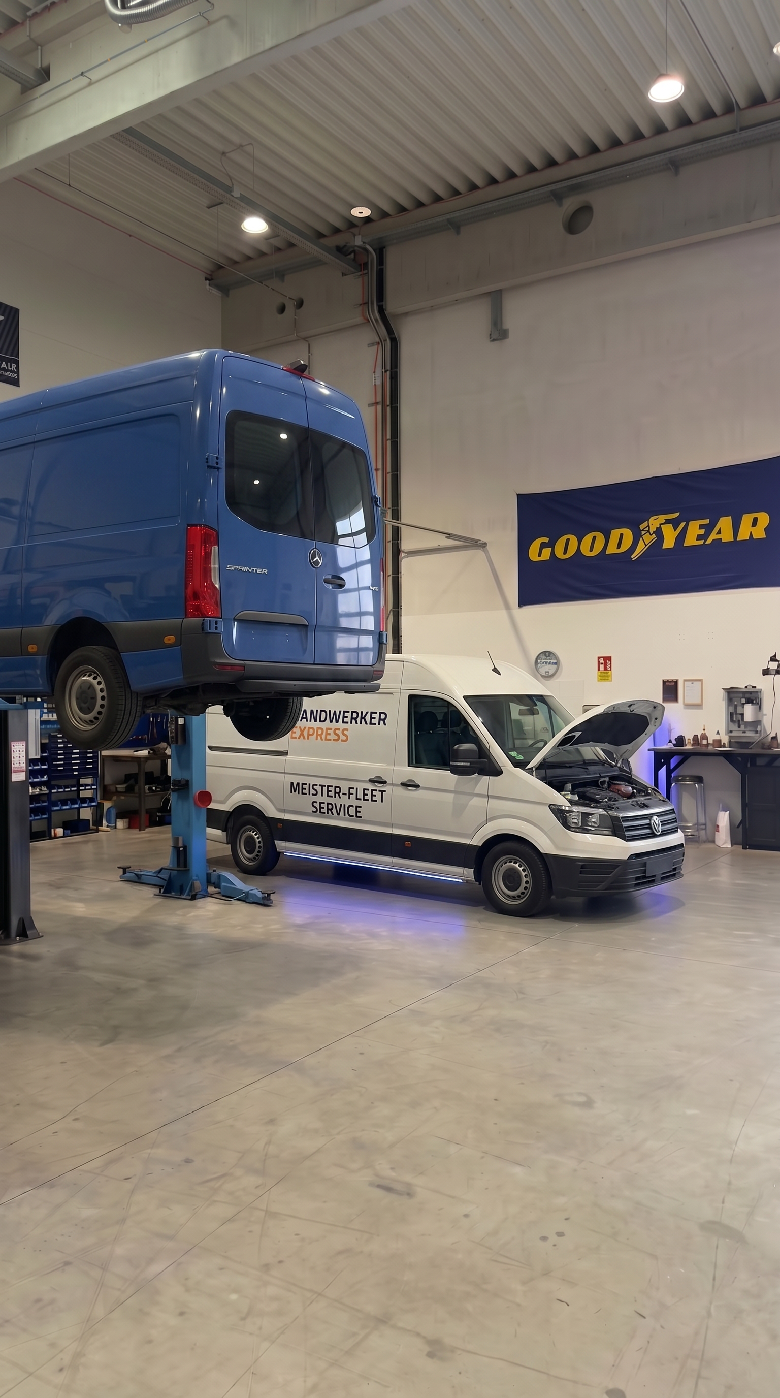 Ein blauer Lieferwagen wurde in einer Goodyear-Autowerkstatt mit einem hydraulischen Hebezeug