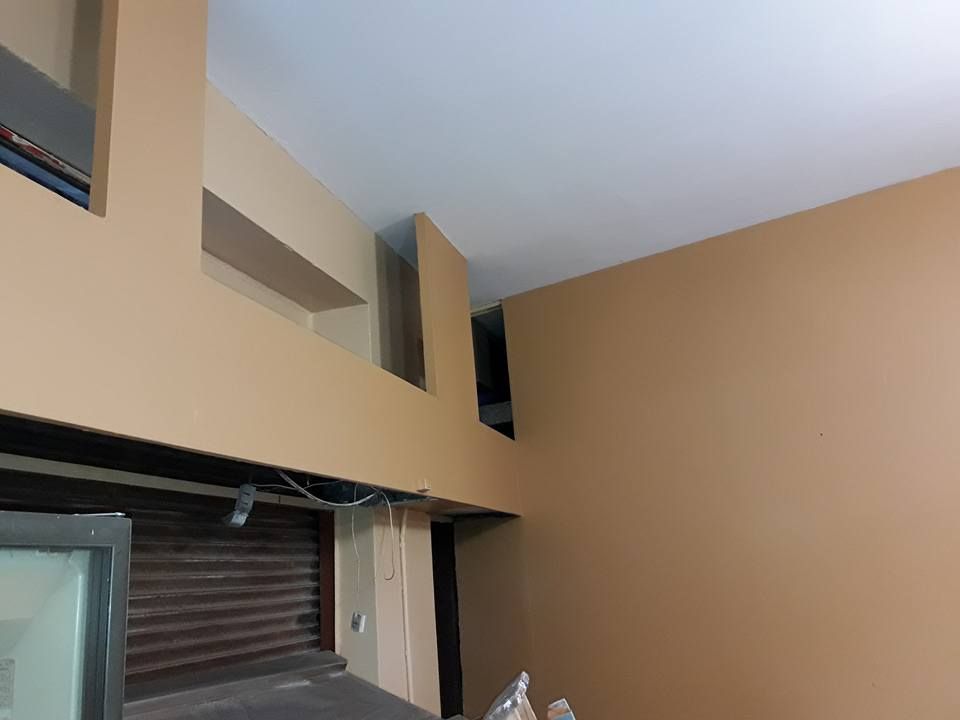 Habitación interior con paredes beige y ventanas rectangulares altas sobre una puerta o abertura tipo garaje.