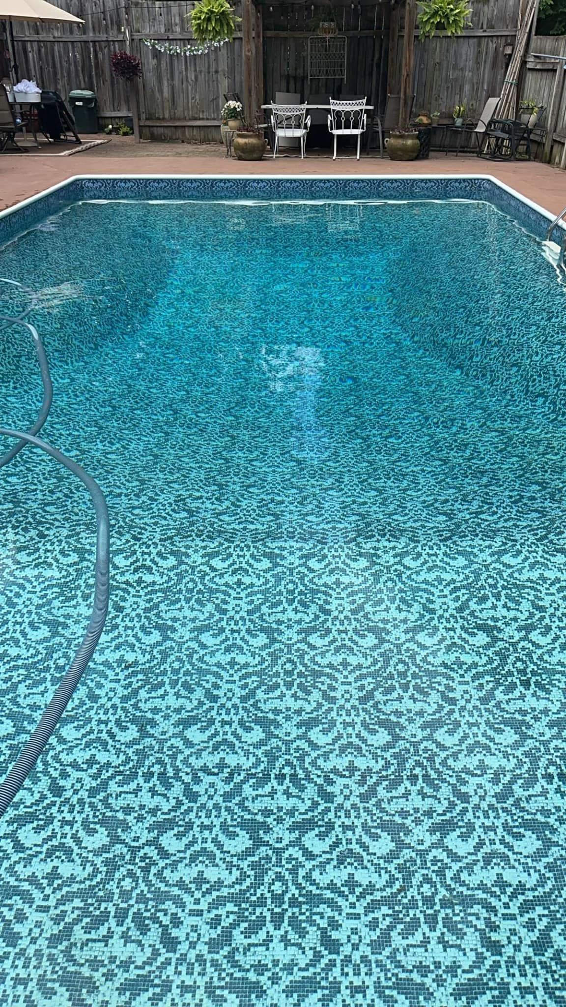 Rectangular pool filled with blue water; a garden patio is visible in the background.