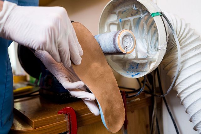 In un'officina, una persona con i guanti bianchi tiene in mano una soletta ortopedica personalizzata