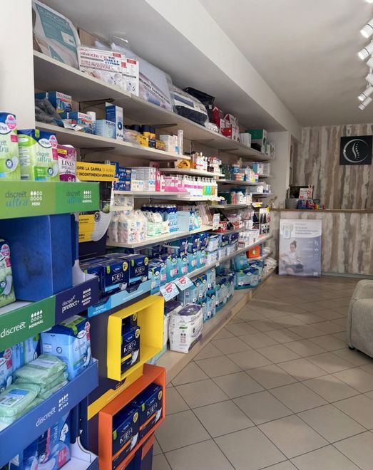 Scaffali di un negozio al dettaglio pieni di vari prodotti per la cura dei bambini e pannolini, con un bancone sullo sfondo.