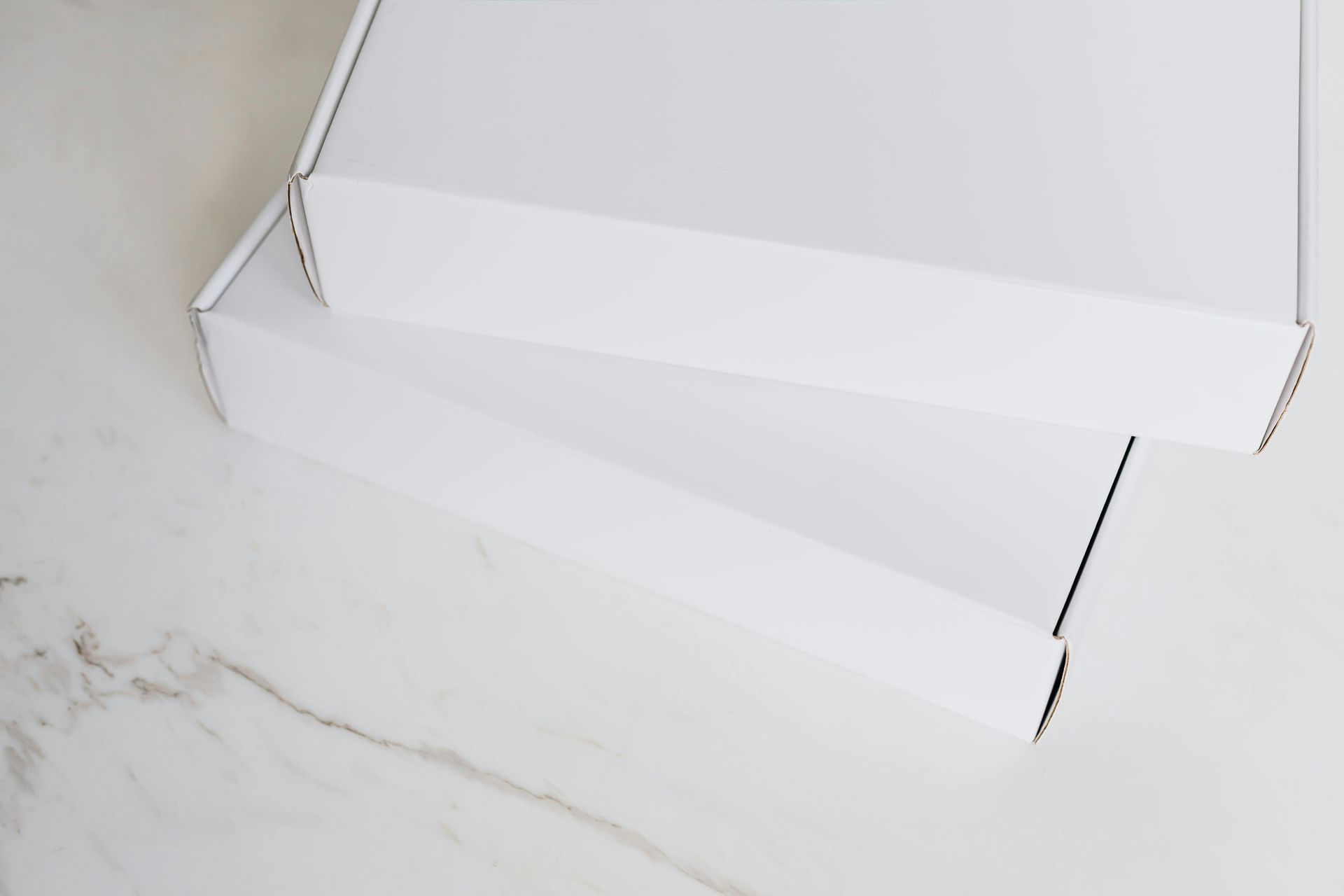 Duas caixas de papelão brancas empilhadas sobre uma superfície de mármore.