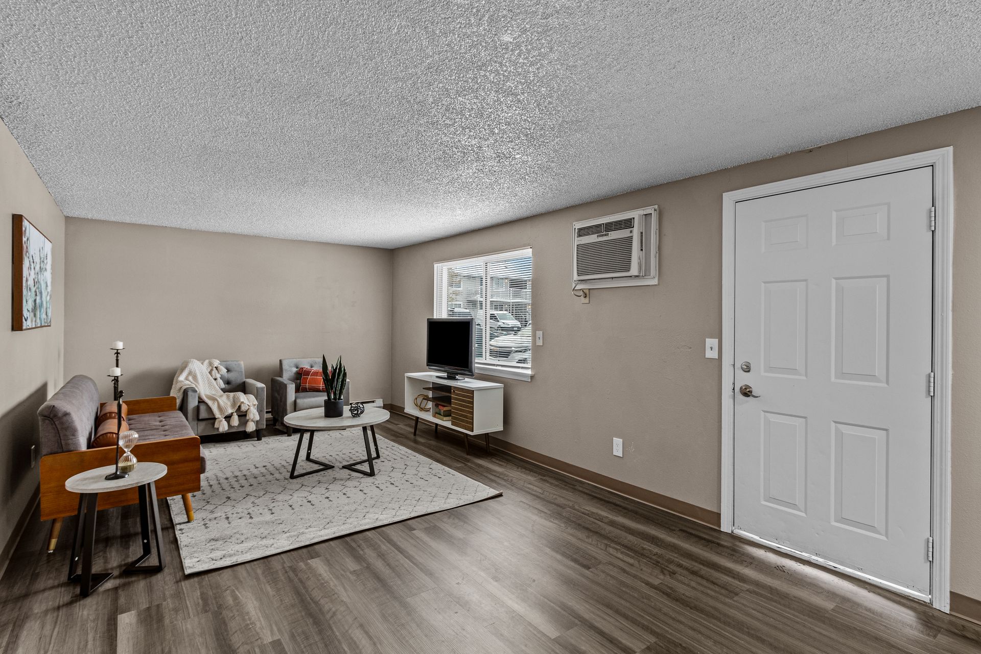 Living room with gray walls, white door, sectional sofa, TV, coffee table, and patterned rug
