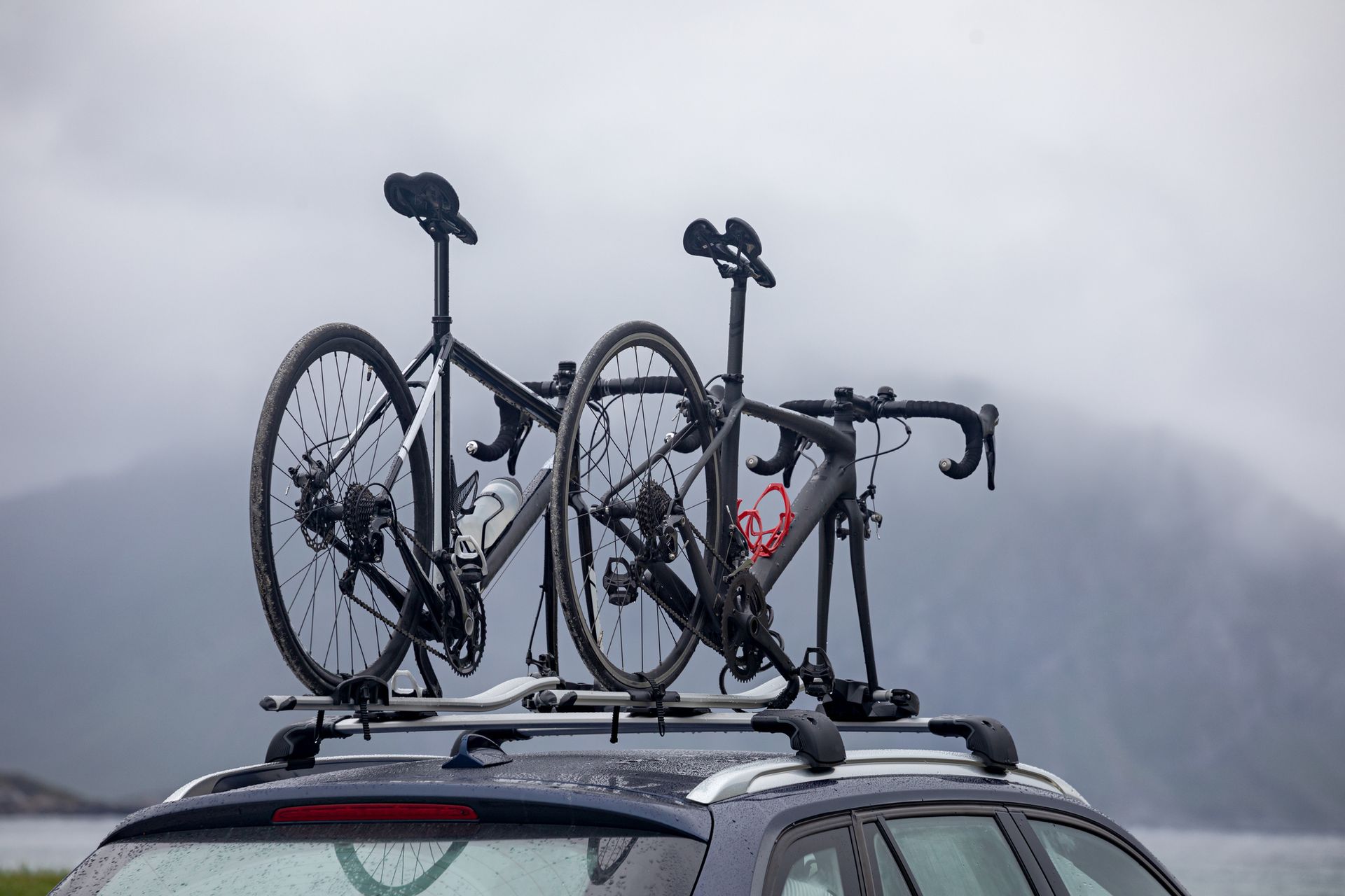 Two bicycles are sitting on top of a car.