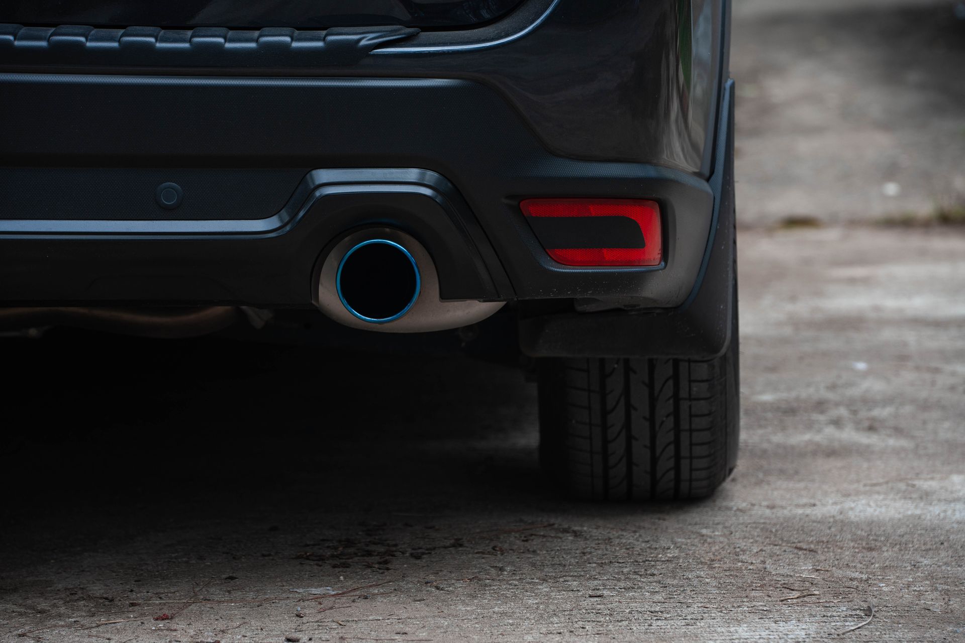 A close up of the exhaust pipe of a black car.
